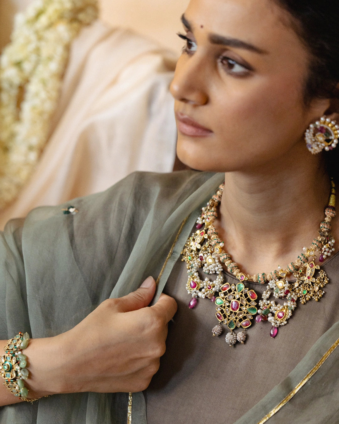 Handcrafted gold polki tukdi necklace featuring a floral pendant, pearl clusters, ruby and emerald accents, nath and fish motifs, fungar detailing, and traditional patwa threadwork.