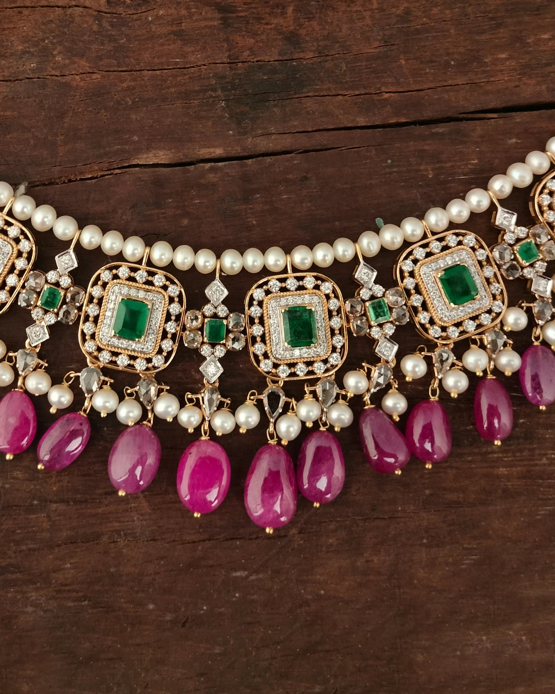 Aesha Necklace in gold featuring emerald-set square motifs framed in brilliant-cut diamonds, pearl strands, and a cultured pearl and ruby drop fringe - handcrafted fine jewellery.