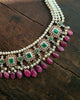 Aesha Necklace in gold featuring emerald-set square motifs framed in brilliant-cut diamonds, pearl strands, and a cultured pearl and ruby drop fringe