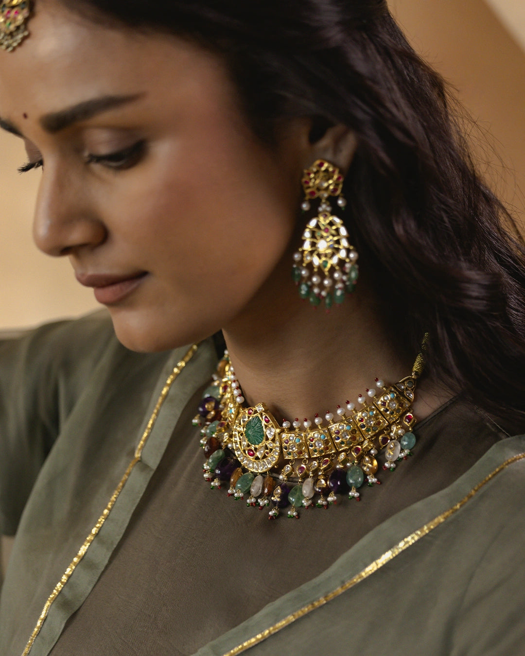 Amer gold Navratna choker necklace featuring polki diamonds, ruby and emerald accents, a chaand motif, hessonite, citrine and emerald gemstone drops, and layered cultured pearl strands.