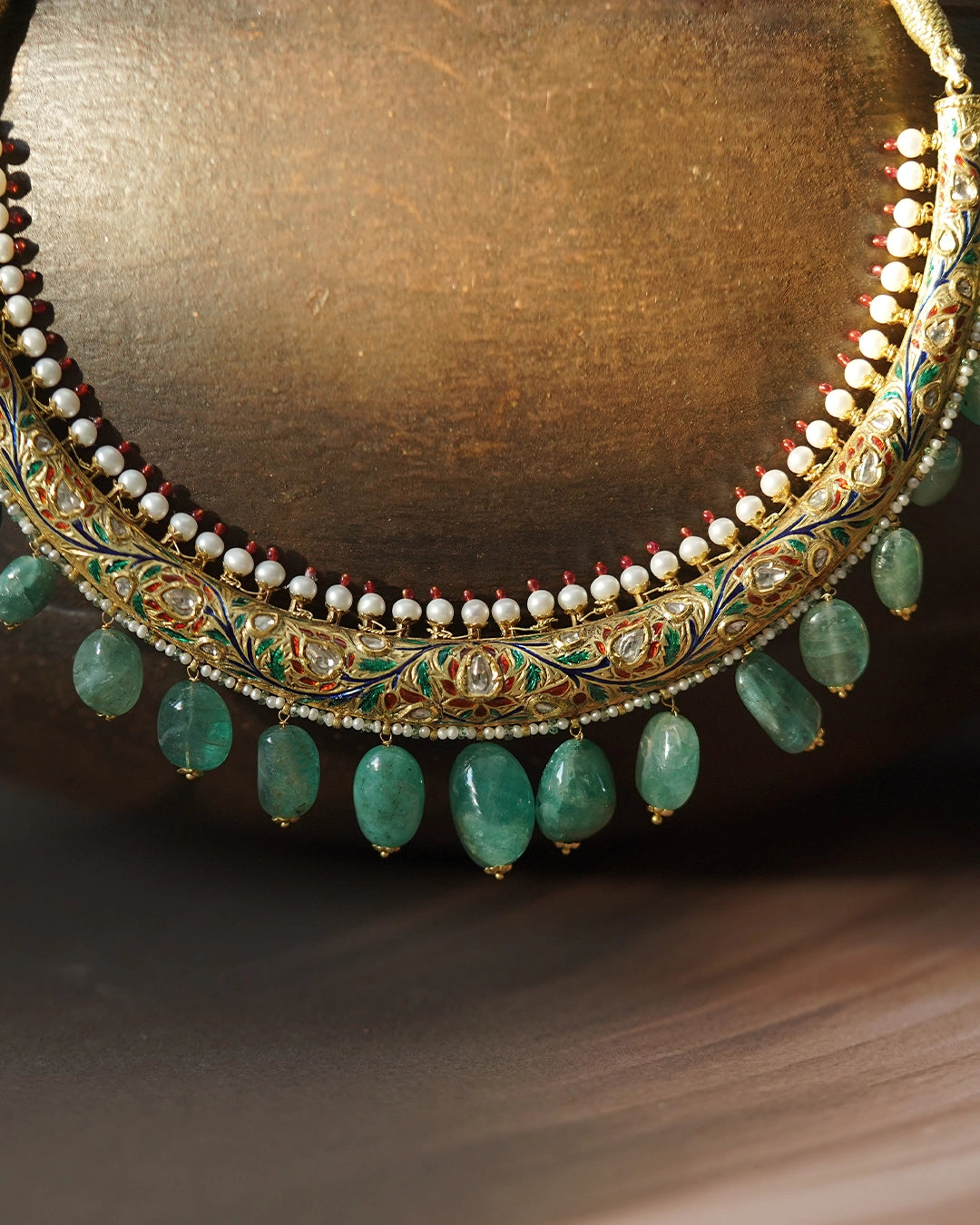 Kashi Hasli rigid gold torque necklace with hand-enamelled red and green floral vine, Polki diamond blooms, cultured pearl border, and graduating emerald drops