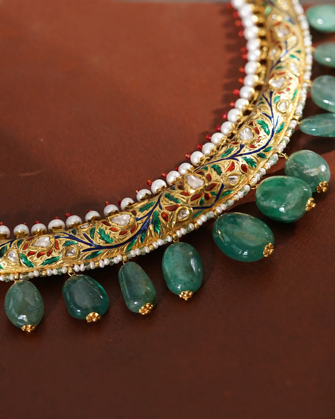 Kashi Hasli rigid gold torque necklace with hand-enamelled red and green floral vine, Polki diamond blooms, cultured pearl border, and graduating emerald drops