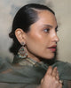 Woman wearing Nehir gold earrings featuring diamonds, emeralds, and cultured pearls