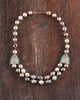 Sanea Necklace featuring multiple strands of cultured pearls with green enamel and rose-cut diamond disks, finished with diamond and emerald clasps